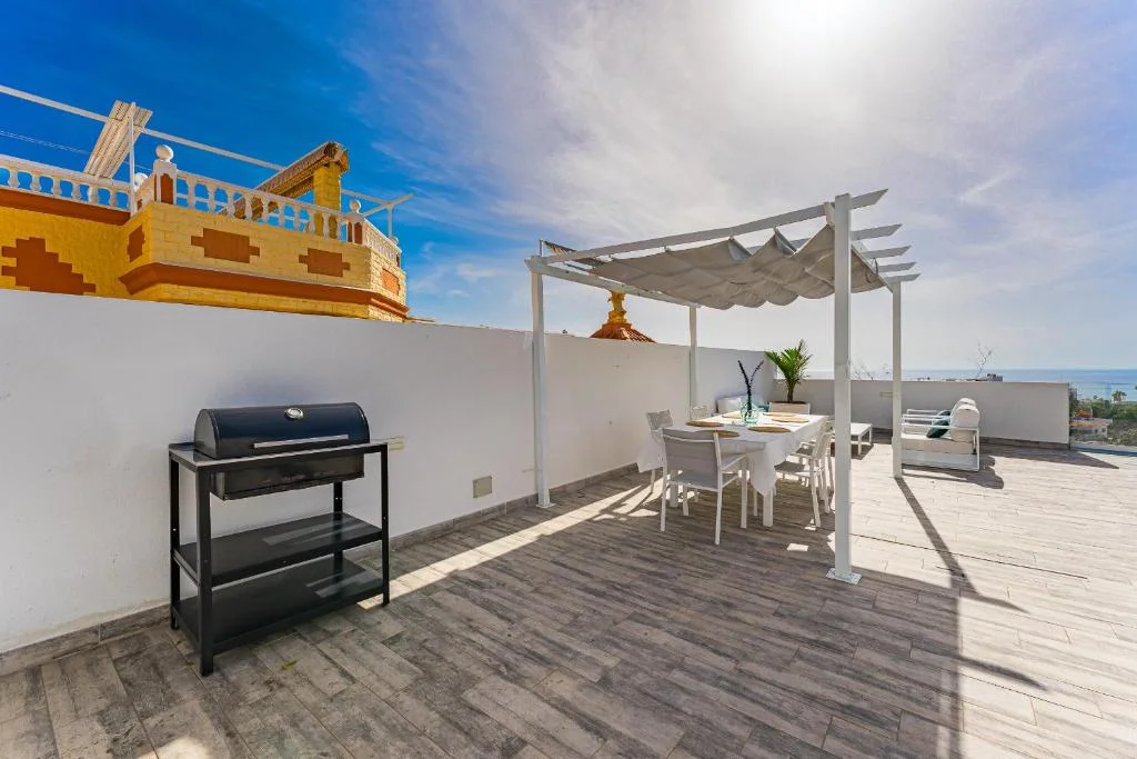Terrace with barbecue and dining area under a pergola